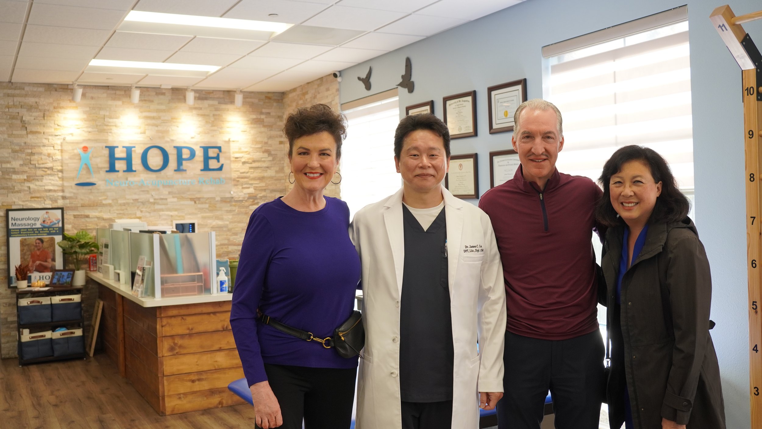 Dr. Lu with patient couple and staff member posing in HOPE Clinic treatment area